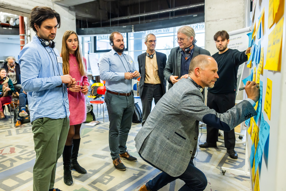 Les participants examinent des post-its sur un mur en discutant entre eux. 