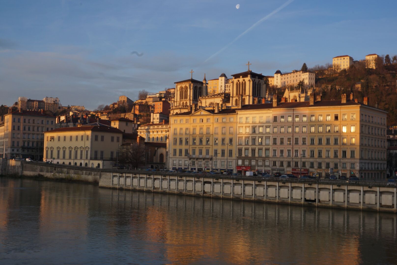 Bord de rivière avec des bâtiments historiques au lever de soleil.