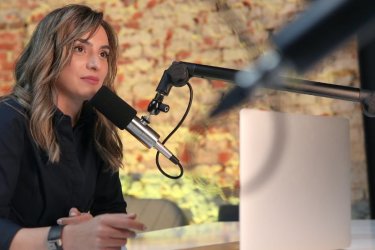 Journaliste devant un microphone et un ordinateur.