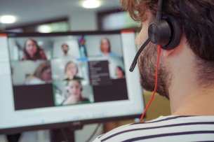 Une tête de profil portant un casque audio, fait face à un écran sur lequel se distinguent plusieurs visages.